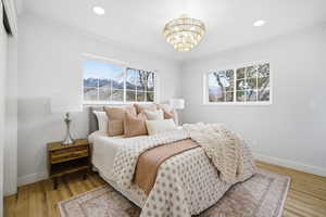 Bedroom with multiple windows, a chandelier, ornamental molding, light wood-type flooring, and recessed lighting