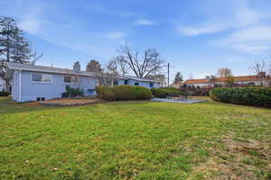 Back of house featuring a chimney, a lawn, and brick siding