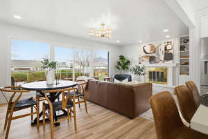 Living area with a brick fireplace, built in shelves, light wood-style floors, a chandelier, and recessed lighting