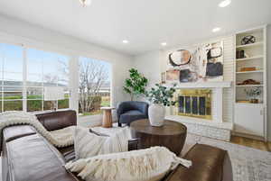 Living room featuring a fireplace, built in features, wood finished floors, and recessed lighting