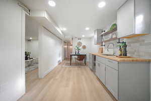 Corridor featuring light wood-style flooring, beverage cooler, and recessed lighting
