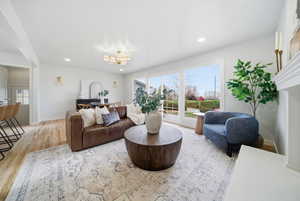Living room with a chandelier, plenty of natural light, light wood-type flooring, and recessed lighting