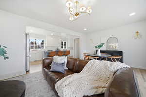 Living room with a chandelier, light wood-style flooring, and recessed lighting