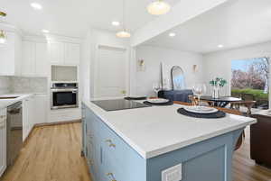 Kitchen with white cabinetry, light stone countertops, blue cabinetry, appliances with stainless steel finishes, and recessed lighting