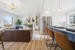 Living area featuring healthy amount of natural light, light wood finished floors, a brick fireplace, a chandelier, and recessed lighting