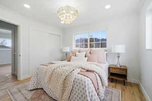 Bedroom featuring a closet, light wood-style flooring, crown molding, a chandelier, and recessed lighting