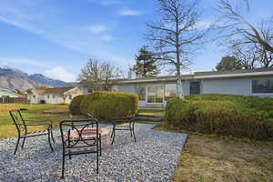 Rear view of house featuring a chimney, a mountain view, an outdoor fire pit, and a lawn