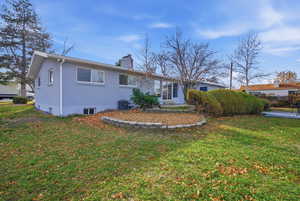 Rear view of property featuring a chimney, a yard, and brick siding