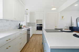 Kitchen with white cabinets, light stone countertops, appliances with stainless steel finishes, hanging light fixtures, and recessed lighting