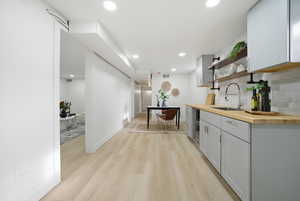 Kitchen with butcher block countertops, open shelves, backsplash, recessed lighting, and light wood finished floors