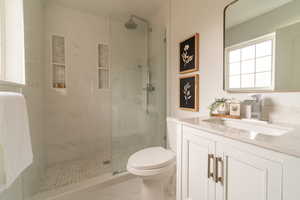 Bathroom with vanity, walk in shower, and light marble finish floors