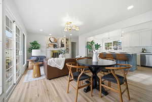 Dining space with a fireplace, light wood-type flooring, a chandelier, and recessed lighting