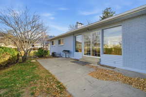 View of home's exterior featuring a chimney, brick siding, and a patio area