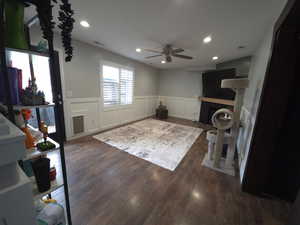 Living area with a wainscoted wall, a fireplace with flush hearth, a decorative wall, dark wood-style floors, and recessed lighting