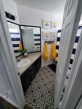 Bathroom with a shower with shower curtain, vanity, and dark tile patterned flooring