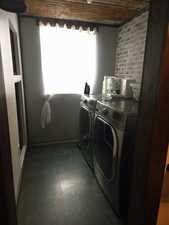 Washroom with separate washer and dryer and brick wall
