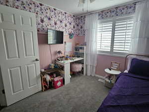 Bedroom featuring wallpapered walls, a wainscoted wall, carpet floors, and a ceiling fan