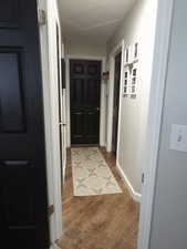 Hallway with wood finished floors and attic access