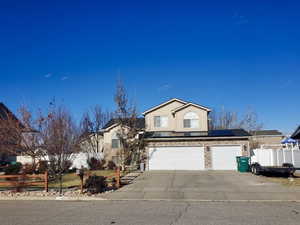 Traditional-style home with solar panels, driveway, and a garage