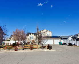 View of front of home featuring roof mounted solar panels and concrete driveway