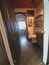 Half bathroom featuring vanity, washing machine and dryer, and wood ceiling