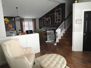 Bar featuring stairs, hanging light fixtures, dark wood-style flooring, and white cabinetry
