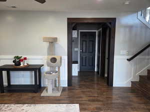 Entryway with a wainscoted wall, stairway, dark wood-style flooring, and a decorative wall
