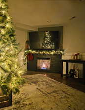 Living room with a warm lit fireplace and dark wood finished floors