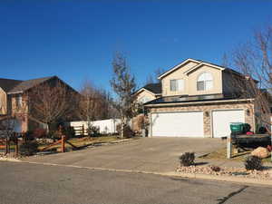 View of front of house with an attached garage, driveway, and brick siding