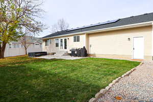 Rear view of house with roof mounted solar panels, a fenced backyard, roof with shingles, a patio, and entry steps