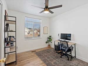 Home office with light wood-type flooring and a ceiling fan