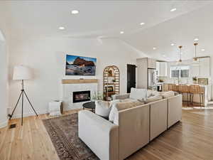 Living area with a tile fireplace, recessed lighting, vaulted ceiling, and light wood-style flooring