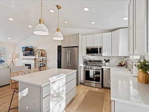 Kitchen with a kitchen breakfast bar, open floor plan, stainless steel appliances, lofted ceiling, and hanging light fixtures