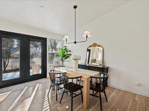 Dining space featuring vaulted ceiling, light wood-style flooring, and french doors