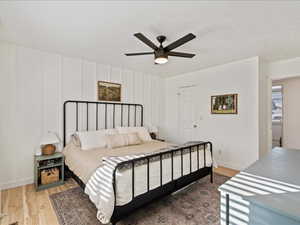 Bedroom with a decorative wall, a ceiling fan, and light wood-style floors
