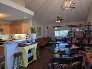 Kitchen featuring open floor plan, lofted ceiling, a barn door, a textured ceiling, and a breakfast bar