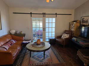 Living room with dark wood-style flooring, a barn door, and a textured ceiling