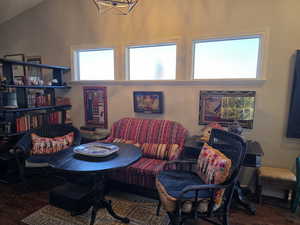 Living area featuring wood finished floors, lofted ceiling, and a chandelier