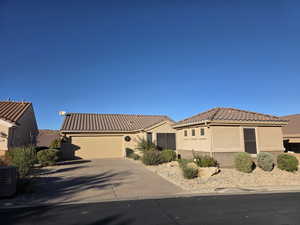 Mediterranean / spanish house featuring  a CASITA, stucco siding, a tiled roof, concrete driveway, and an attached garage