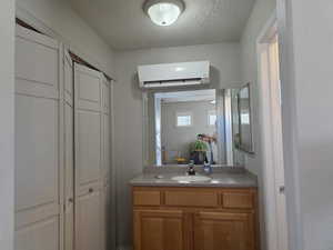 3rd Bathroom  in Casita featuring a closet, vanity, a wall mounted air conditioner, and a textured ceiling