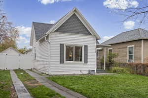 Rear view of house featuring a gate, a lawn, and a shingled roof
