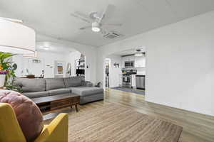 Living room featuring a ceiling fan, light wood-style flooring, and arched walkways