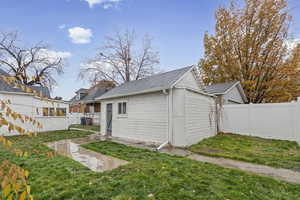 Rear view of house featuring an outbuilding, a fenced backyard, and a shingled roof
