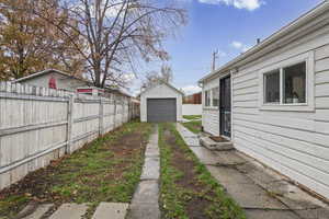 View of yard featuring a garage, an outbuilding, and driveway