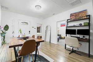 Dining room with light wood-style flooring, arched walkways, and a desk