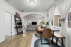 Dining area with arched walkways, light wood finished floors.