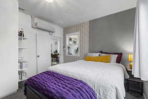 Carpeted bedroom featuring a wall mounted air conditioner.