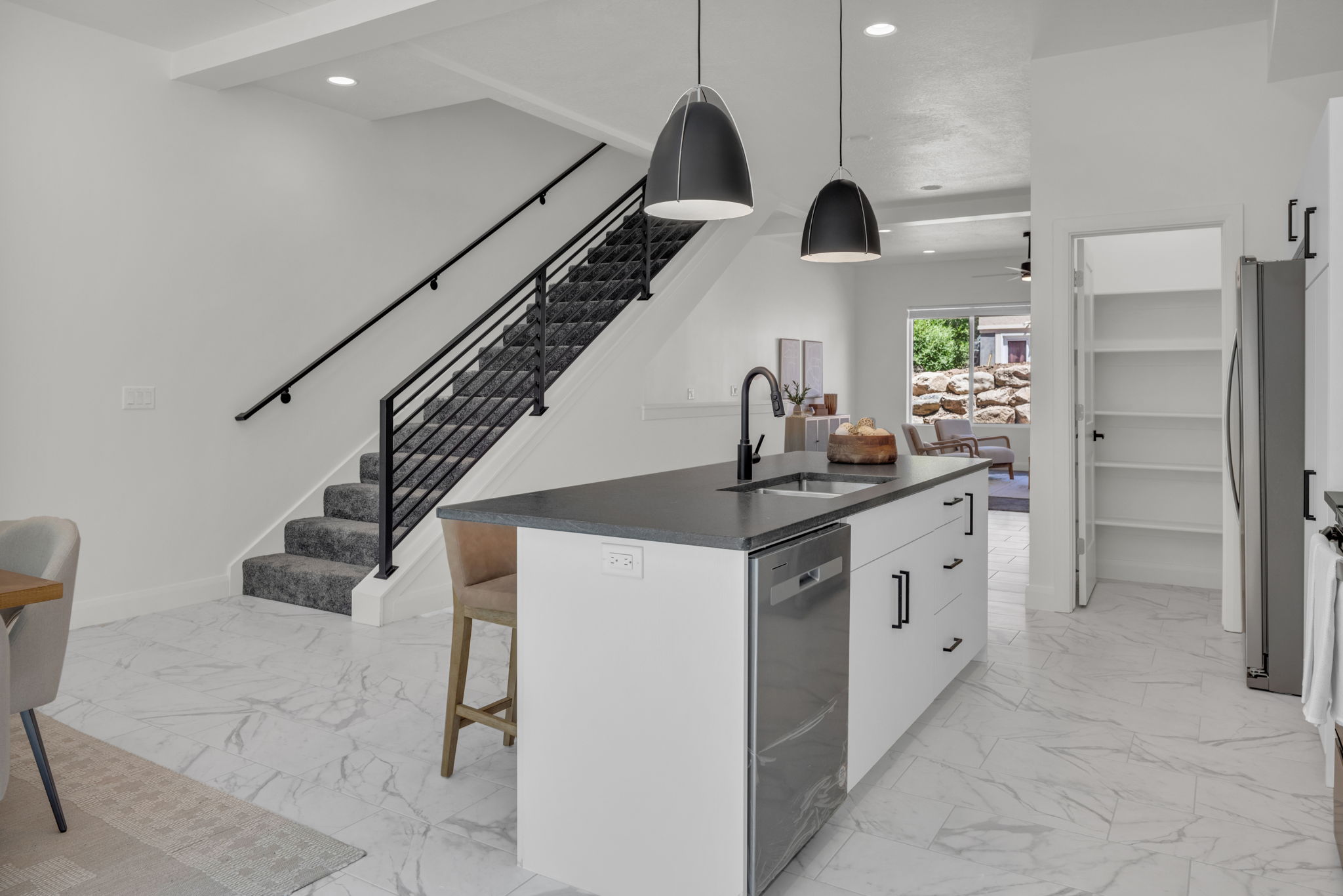Kitchen with white cabinets, a center island with sink, a breakfast bar, pendant lighting, and appliances with stainless steel finishes