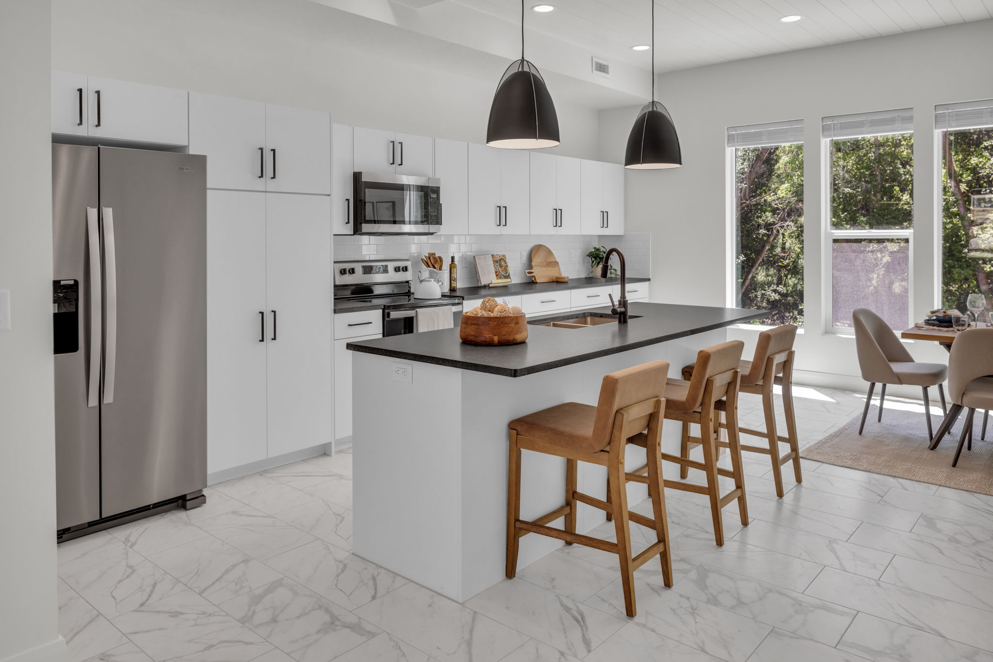 Kitchen featuring stainless steel appliances, light marble finish flooring, a center island with sink, a kitchen bar, and recessed lighting