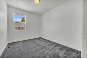 Unfurnished room featuring dark colored carpet and baseboards